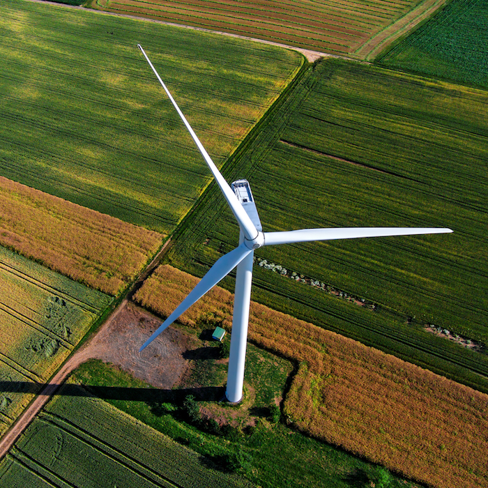 Aerial view of a single wind turbine in a field