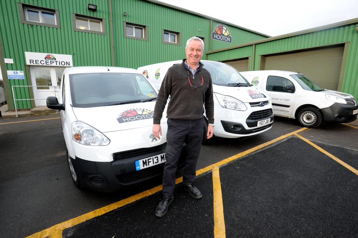 Man stood outside a work environment reception in front of 3 branded vans