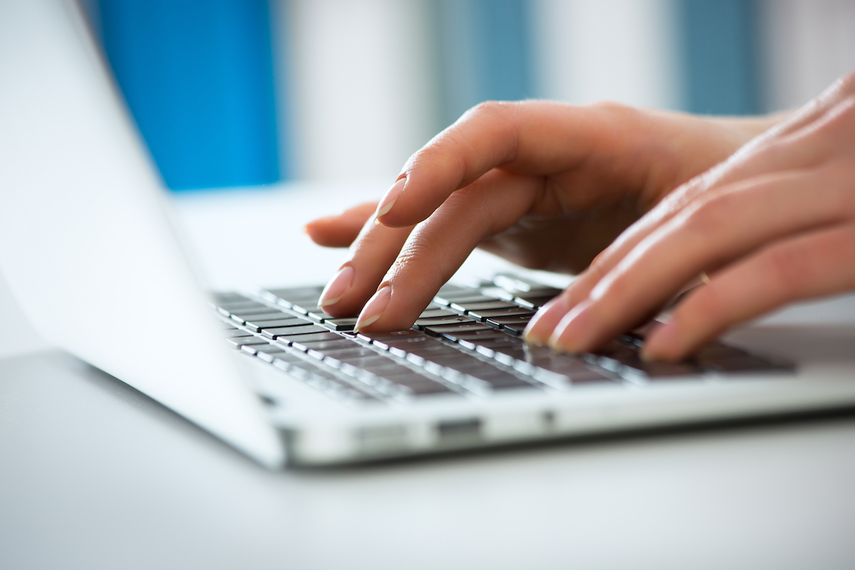 Hands typing on a laptop keyboard