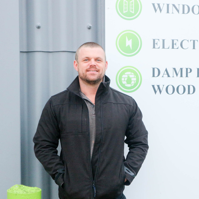 Man stood in front of signage for windows and doors, electrical and testing, damp proofing & wood treatment