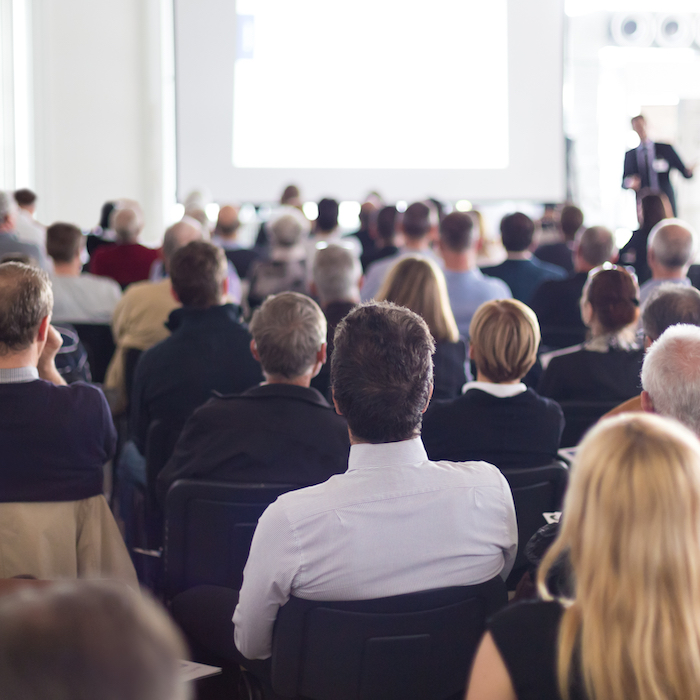 Large group of people sat down at an event listening to a presentation