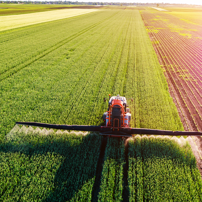 Aerial view of a crop sprayer in a field in bright sunshine
