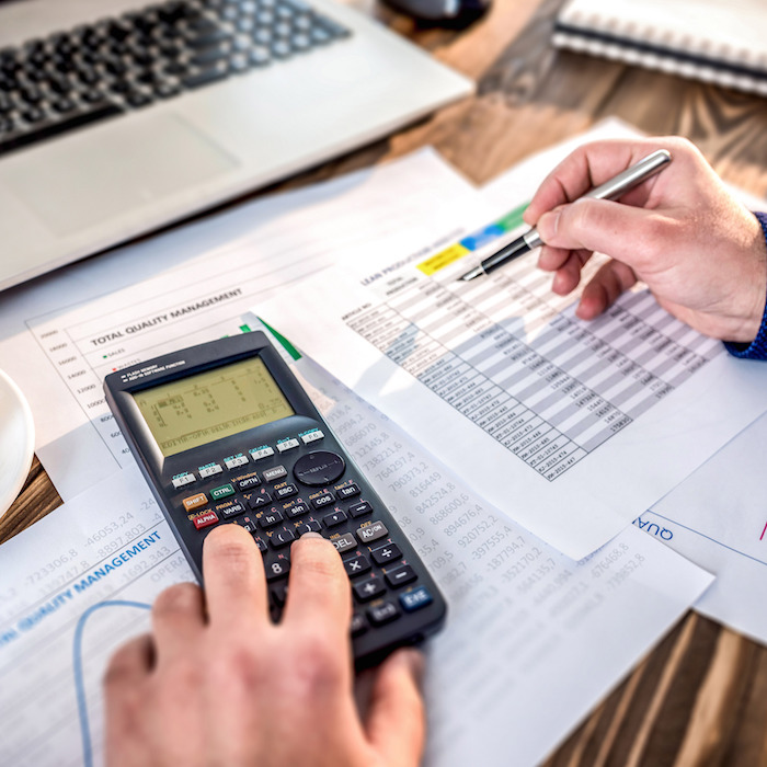 Man working on a scientific calculator and also using printed documents