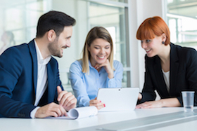 2 ladies and 1 gentleman in business attire seated around a laptop