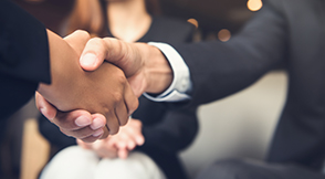 2 people wearing business attire shaking hands