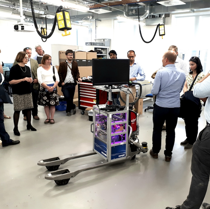 Group of people watching demonstration of tech equipment being used.