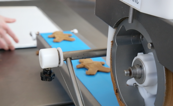 Gingerbread men biscuits being cut out using a machine