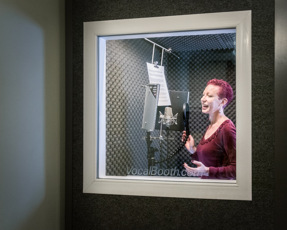 Lady in front of microphones in soundproofed vocal booth