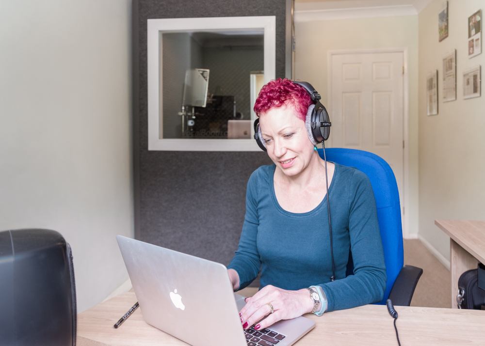 Lady in home office wearing headphones and working on laptop