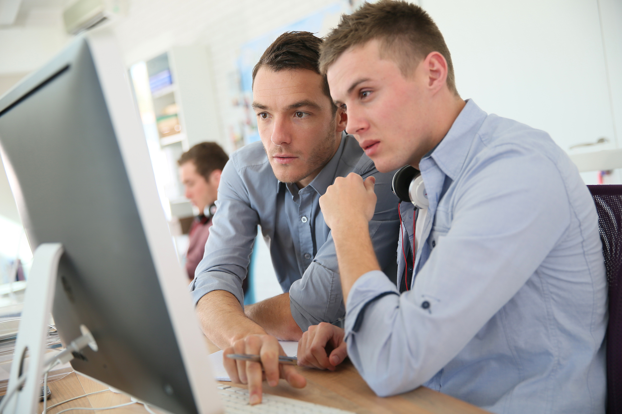 Two people sat at a desk working on a computer