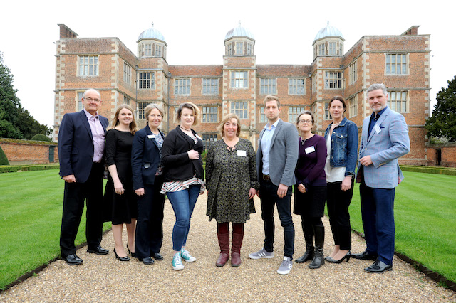 Group of 9 people stood in front of a large house