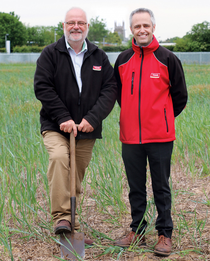 Two gentleman stood in field with shovel