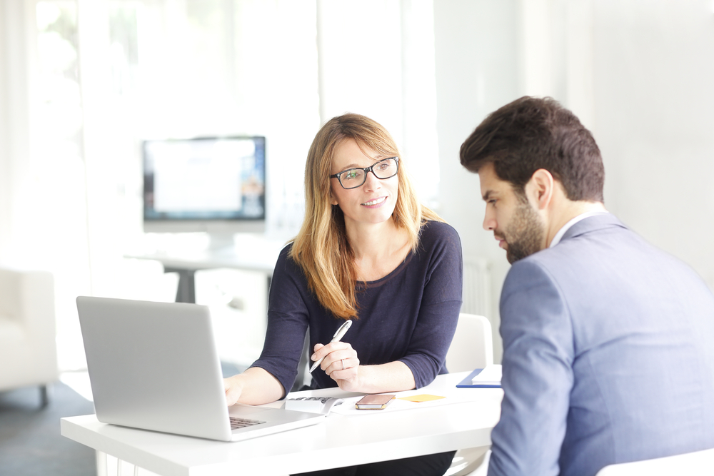 Two people talking sat around a laptop