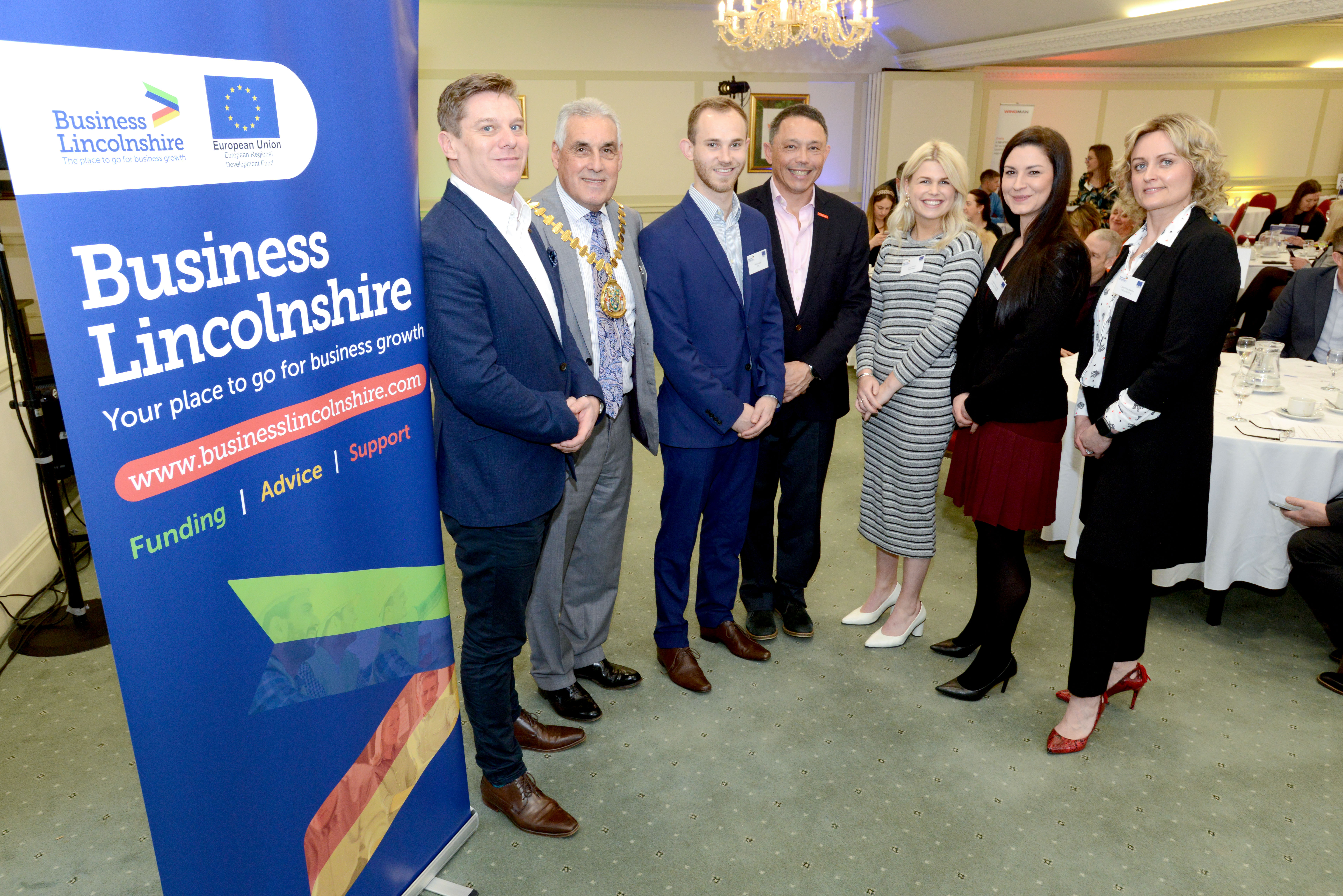 4 gentleman and 3 women stood next to Business Lincolnshire banner at an event