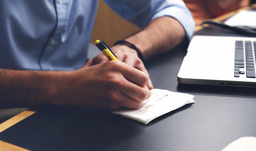 Image of man writing on paper sat at desk