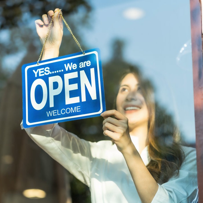 Women displaying open sign in window