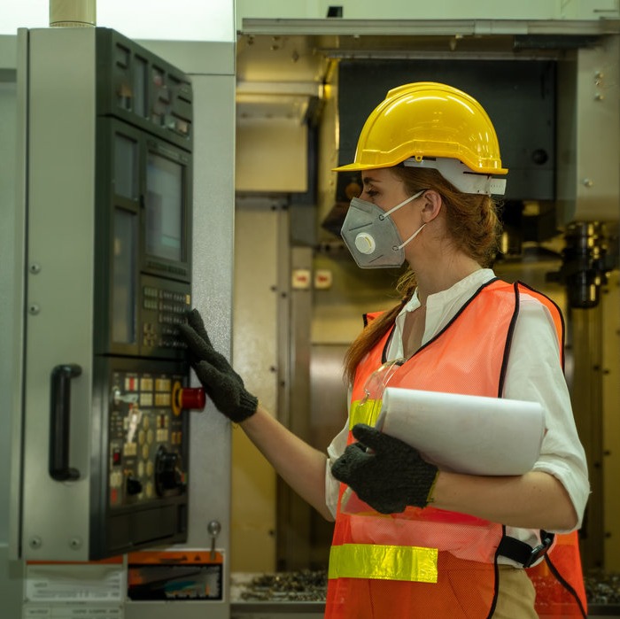 Women in construction work gear using manufacturing equipment