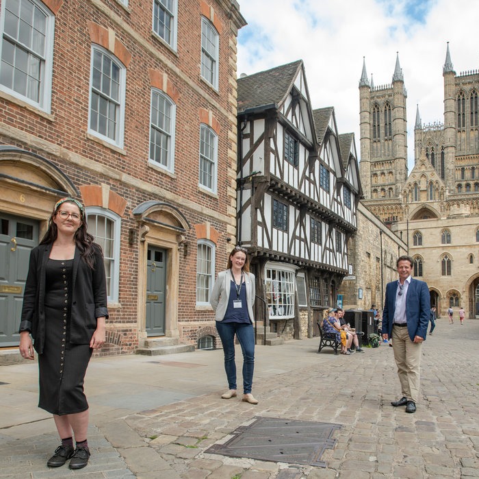 2 ladies and a gentleman stood on Lincoln High Street in front of Cathedral