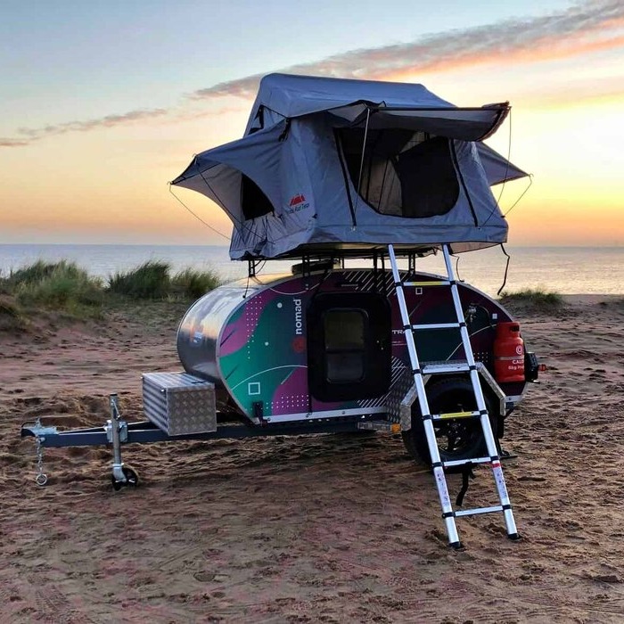 Tent on top of a trailer with ladder up to tent.