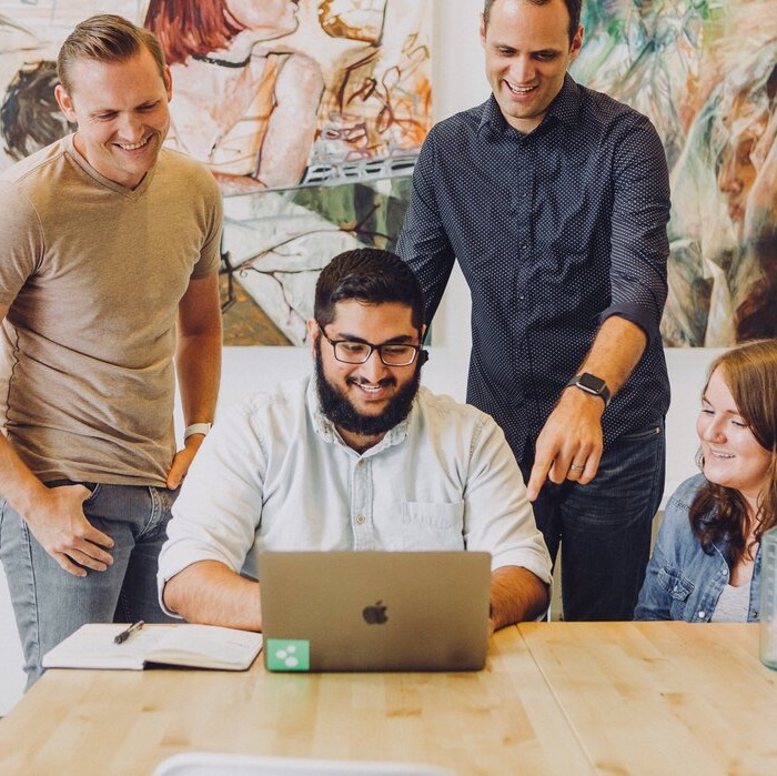 3 gentlemen and 1 women sat around laptop