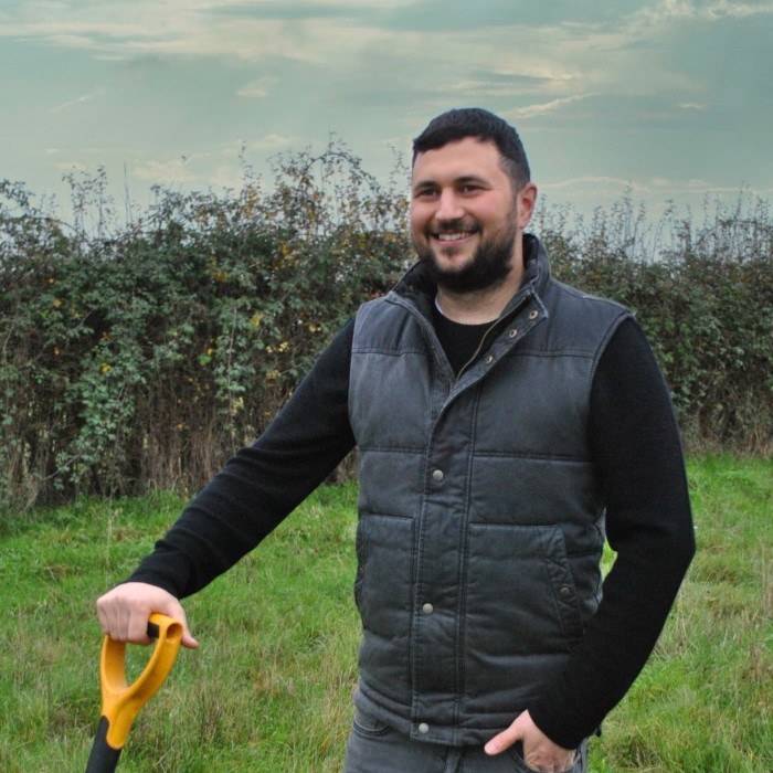 Owner or My Square Metre smiling with spade in field