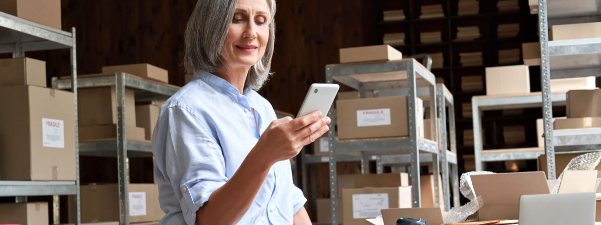 Business owner holding a phone in a stockroom of a warehouse